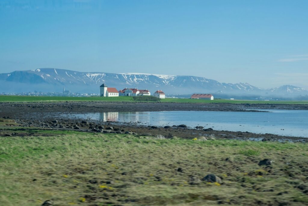 a large body of water sitting next to a lush green field